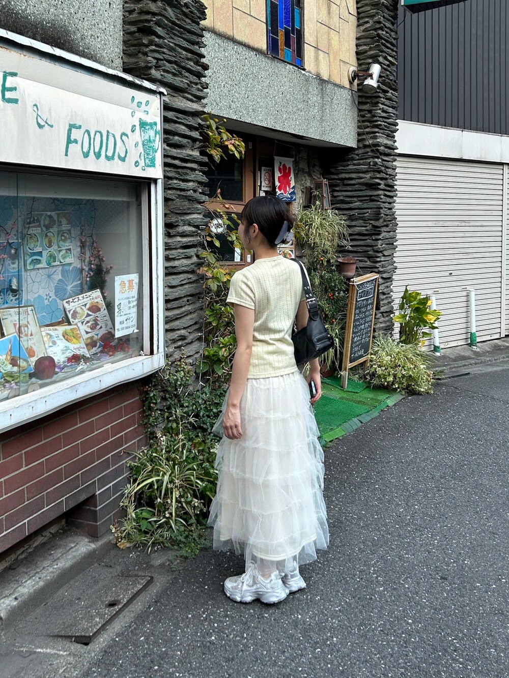 イエロー系のトップス、ホワイト系のスカート、シルバー系のスニーカーを着用したレディースの秋コーディネートの2枚目の写真