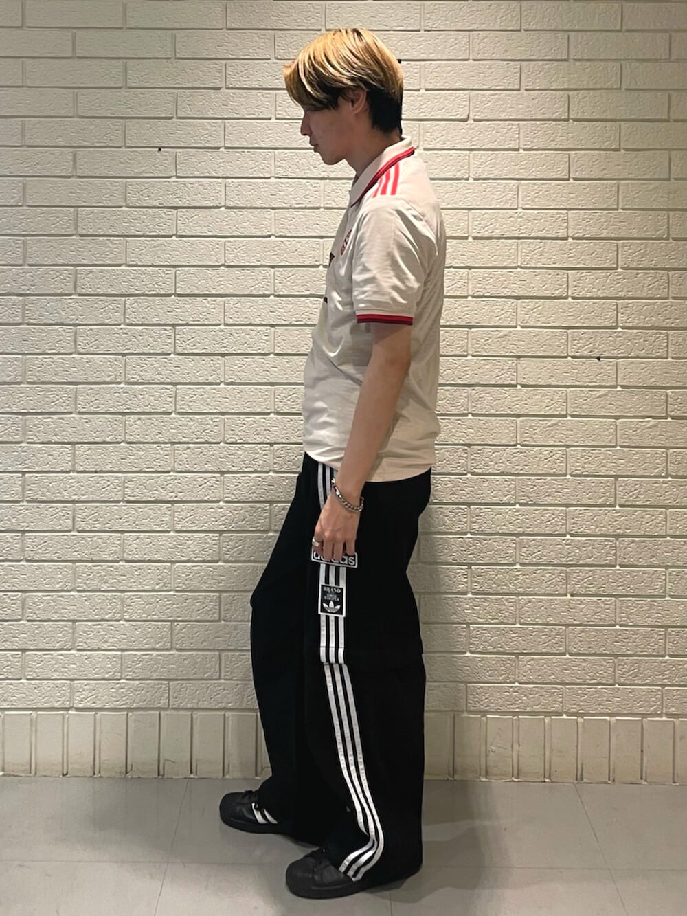 ブラック系のスニーカー、ブラック系のデニムパンツ、ベージュ系のTシャツ/カットソーを着用したメンズの春コーディネートの2枚目の写真