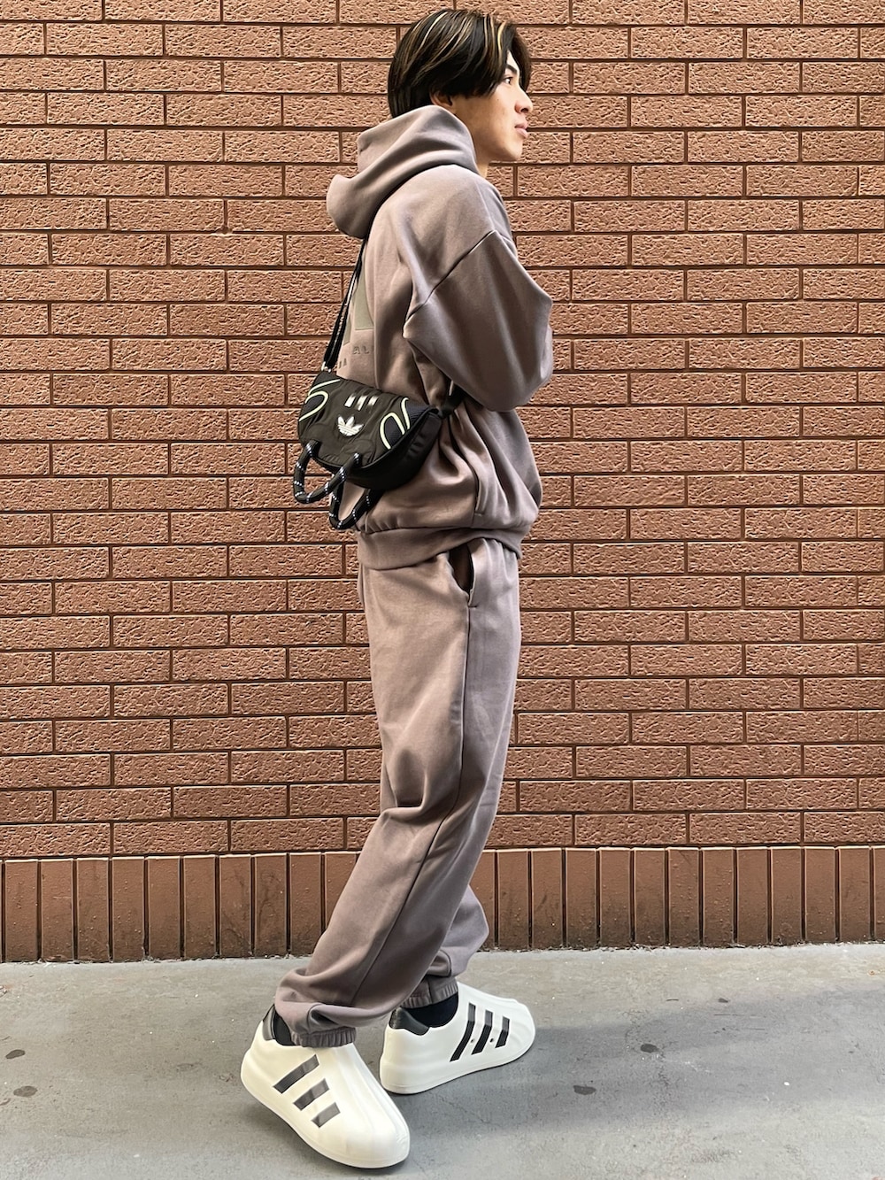 グレー系のパンツ、グレー系のトップス、ブラック系のショルダーバッグを着用したメンズの冬コーディネートの2枚目の写真