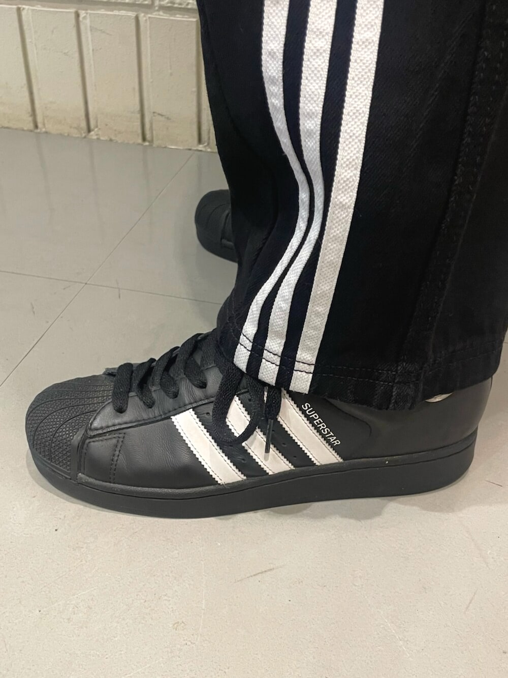 ブラック系のスニーカー、ブラック系のデニムパンツ、ベージュ系のTシャツ/カットソーを着用したメンズの春コーディネートの4枚目の写真