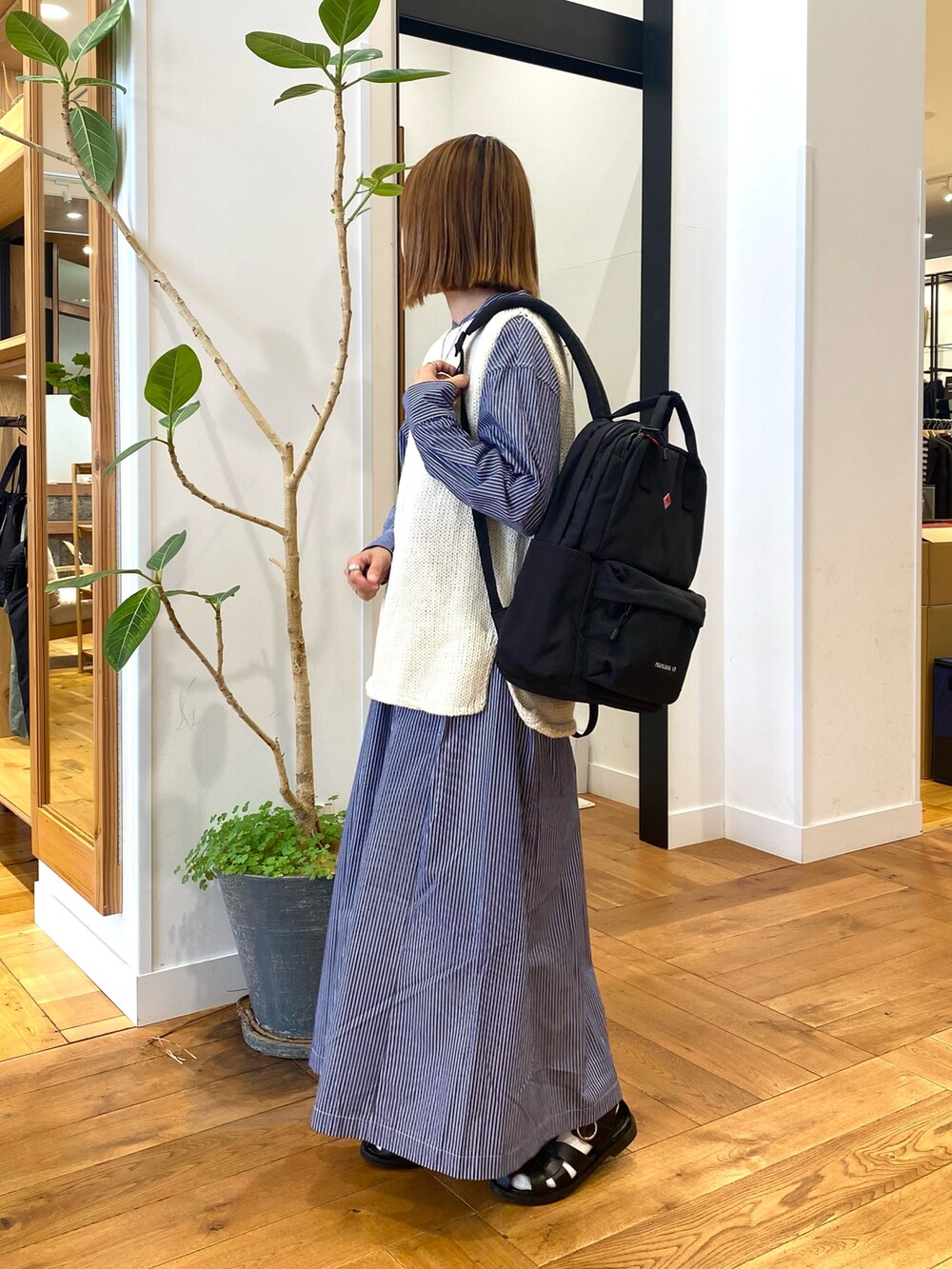 ブルー系のワンピース、ブラック系のバックパック/リュック、ホワイト系のベストを着用したレディースの秋コーディネートの6枚目の写真