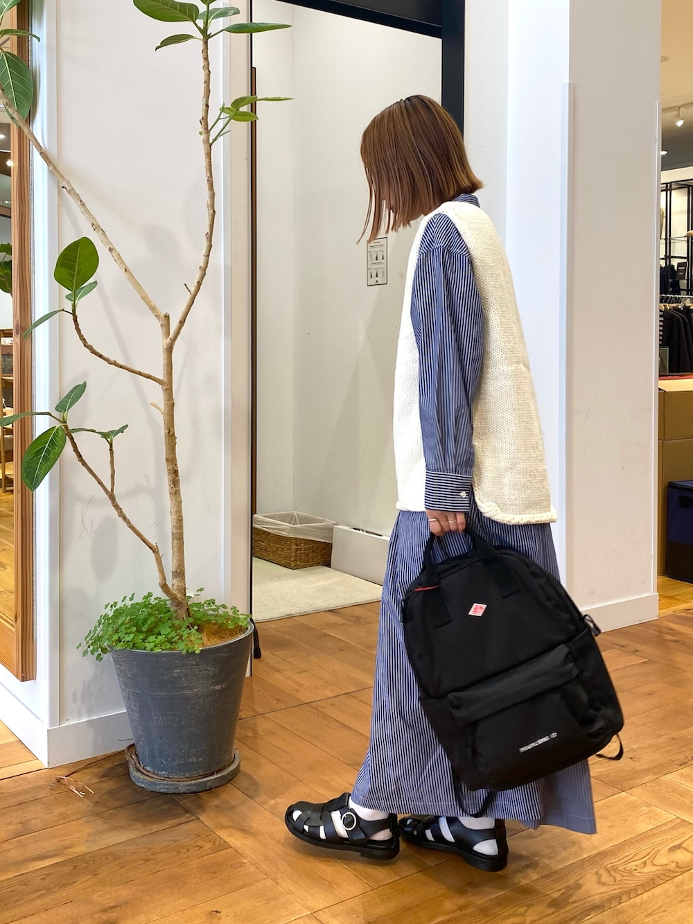 ブルー系のワンピース、ブラック系のバックパック/リュック、ホワイト系のベストを着用したレディースの秋コーディネートの5枚目の写真