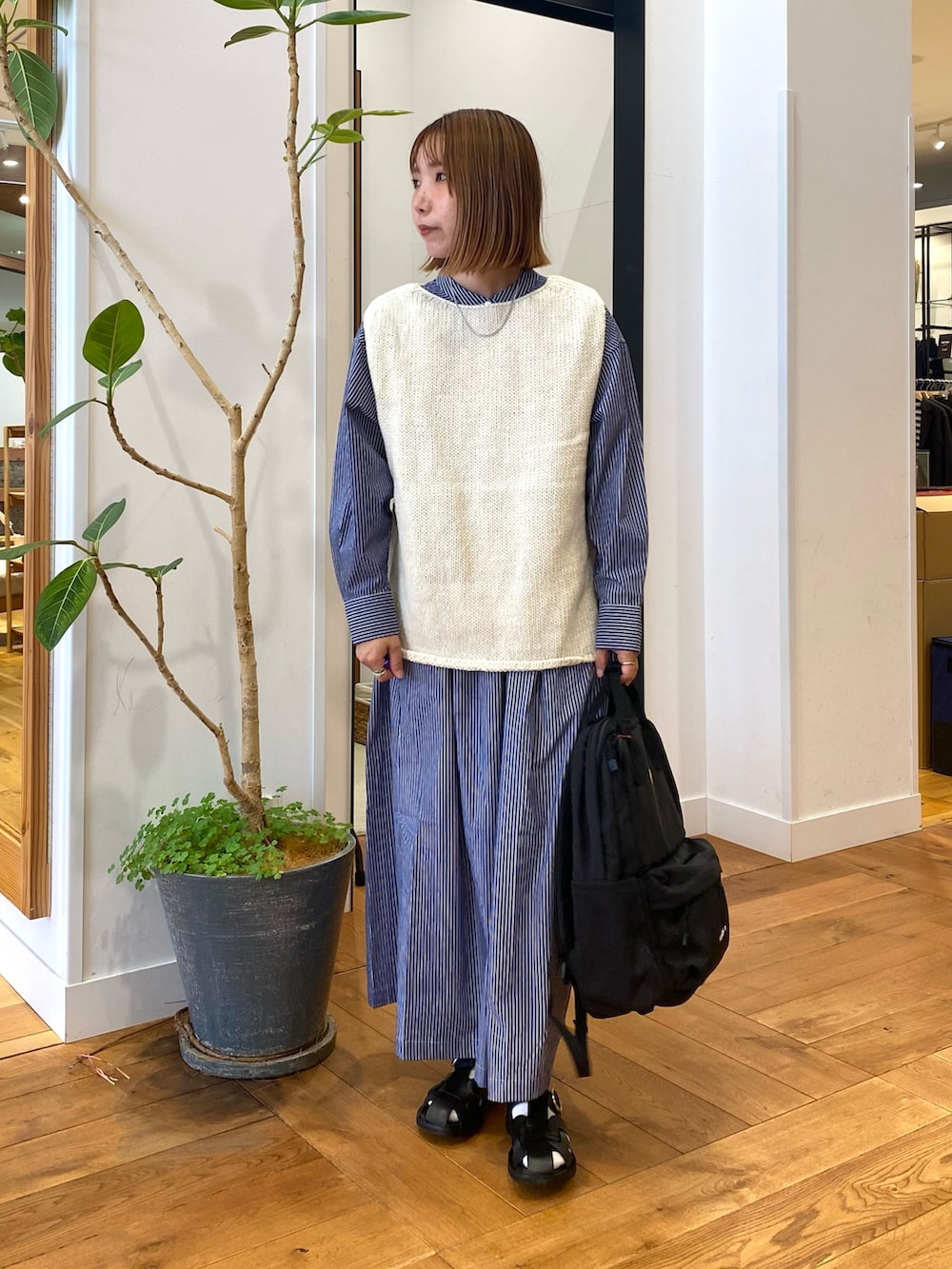 ブルー系のワンピース、ブラック系のバックパック/リュック、ホワイト系のベストを着用したレディースの秋コーディネートの2枚目の写真
