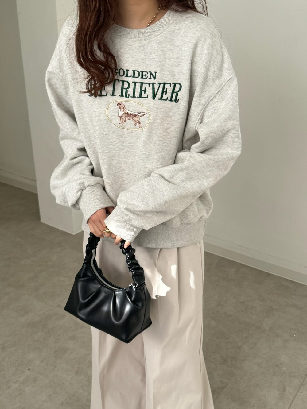 ホワイト系のスウェット、ホワイト系のスラックス、ブラック系のバッグを着用したレディースの春コーディネートの2枚目の写真