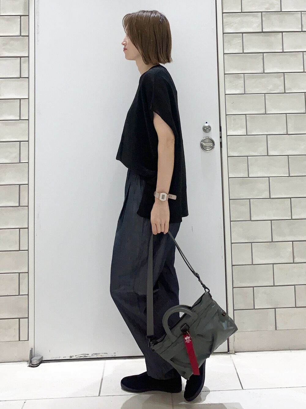 ブルー系のデニムパンツ、ブラック系のトップス、グリーン系のバッグを着用したレディースの夏コーディネートの2枚目の写真