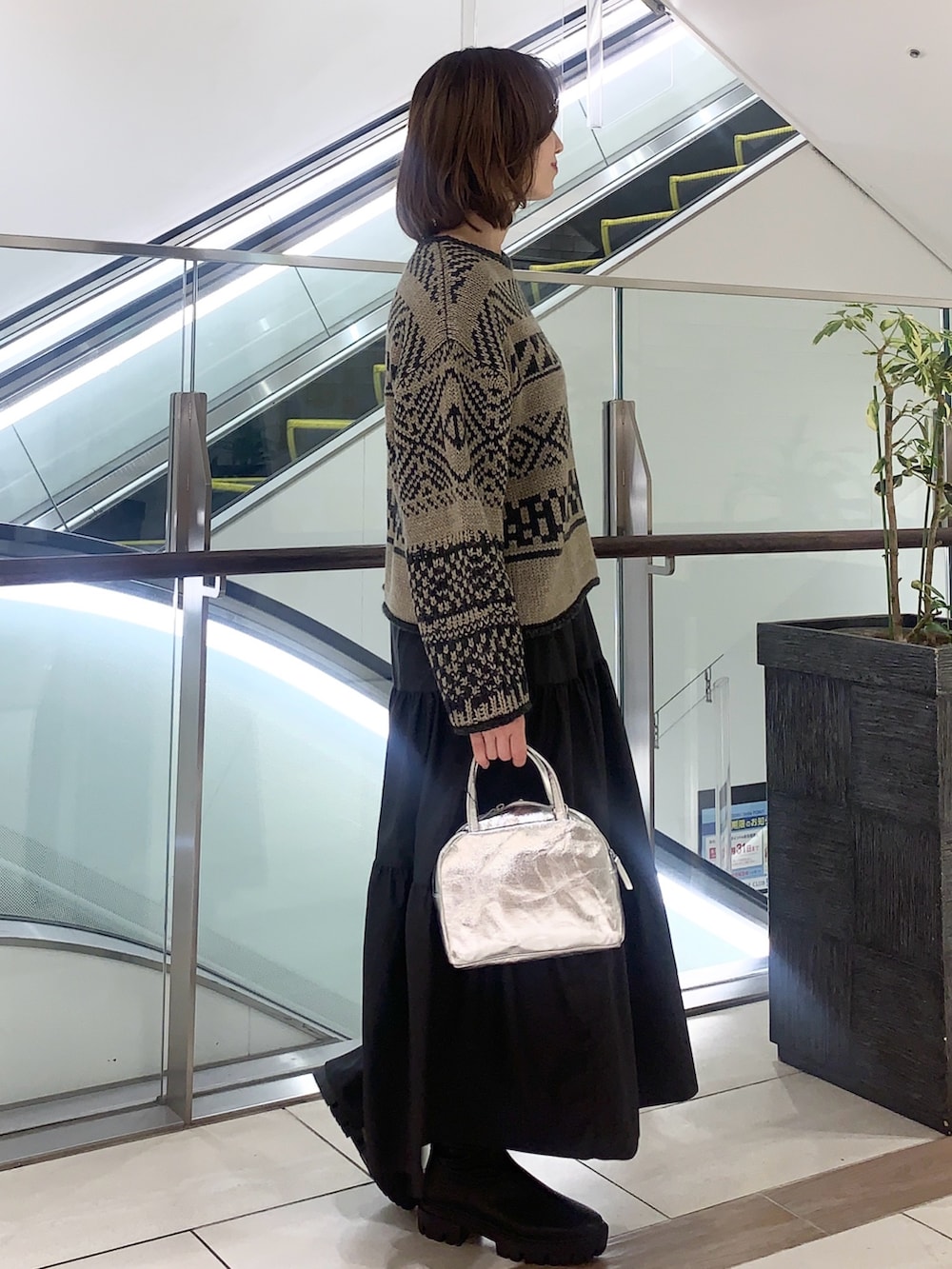 ブラック系のスカート、ベージュ系のニット/セーター、ベージュ系のその他アウターを着用したレディースの冬コーディネートの6枚目の写真