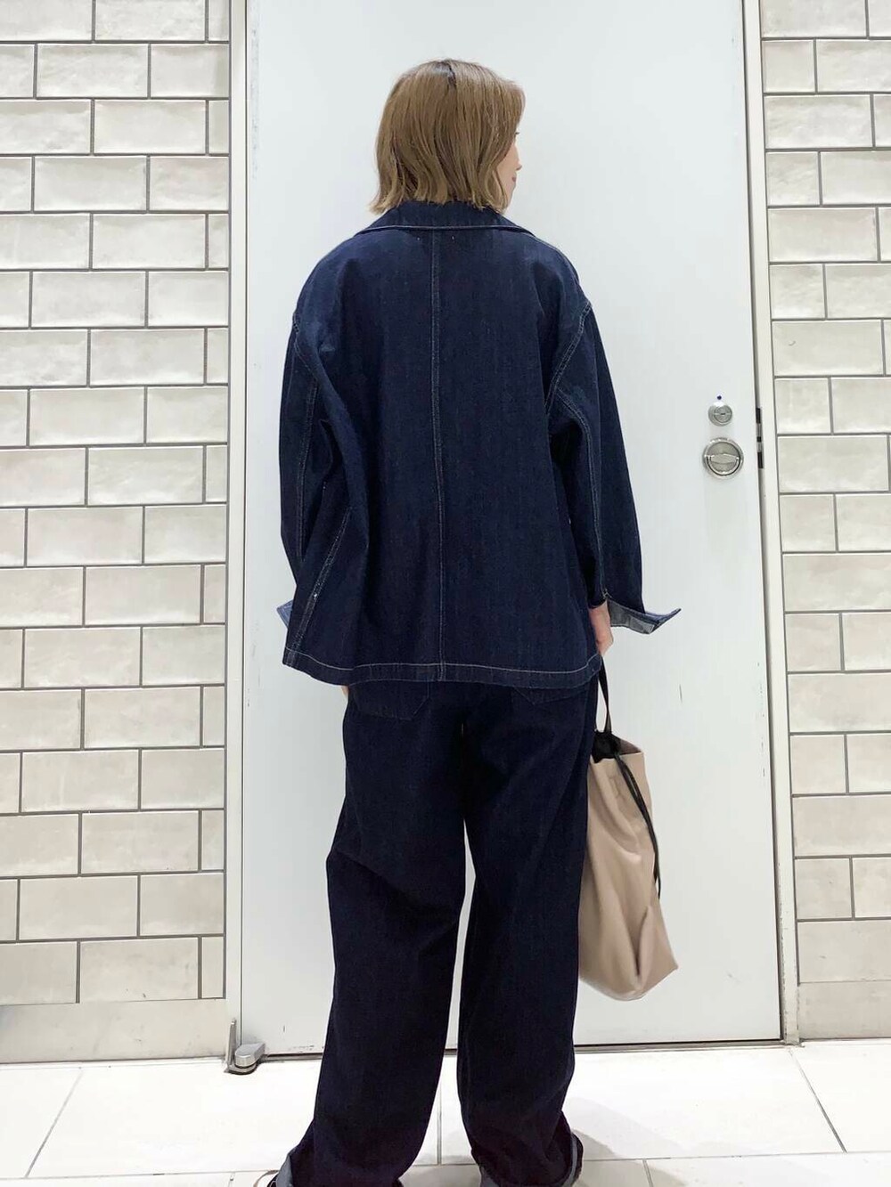 ベージュ系のトートバッグ、イエロー系のタンクトップ、ブルー系のデニムジャケットを着用したレディースの夏コーディネートの3枚目の写真