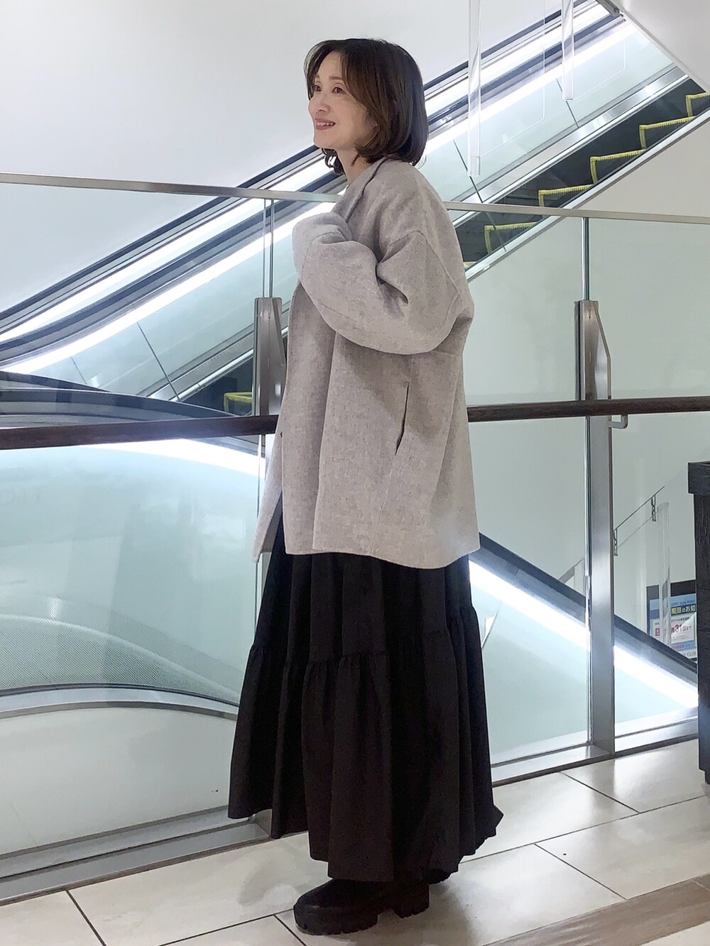 ブラック系のスカート、ベージュ系のニット/セーター、ベージュ系のその他アウターを着用したレディースの冬コーディネートの4枚目の写真