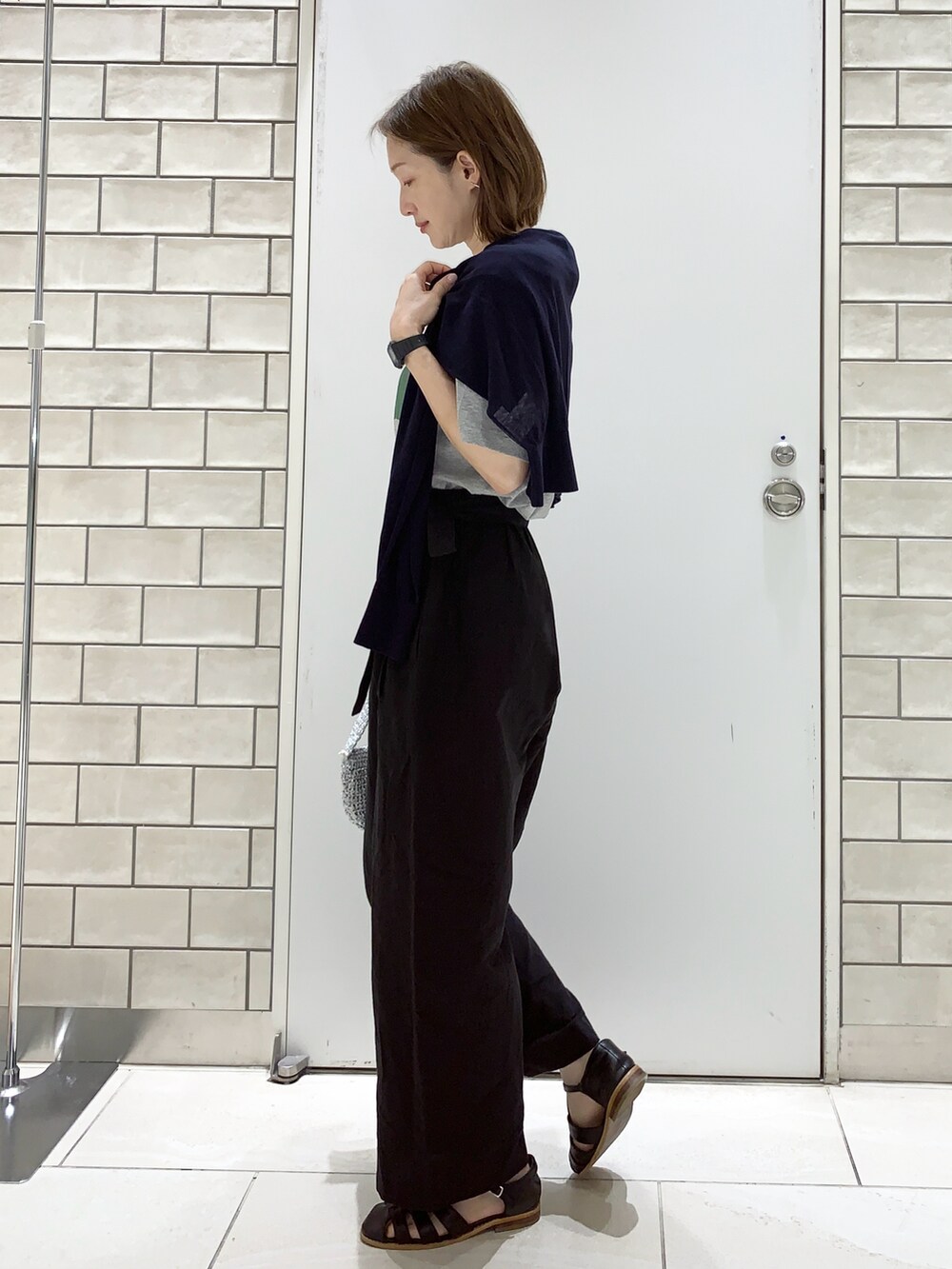 ブラック系のサンダル、ブラック系のパンツ、ブルー系のカーディガン/ボレロを着用したレディースの春コーディネートの2枚目の写真