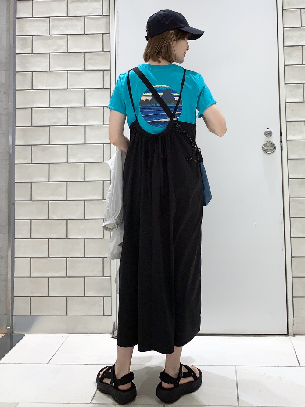 ブラック系のサンダル、ブラック系のワンピース、グレー系のナイロンジャケットを着用したレディースの夏コーディネートの2枚目の写真