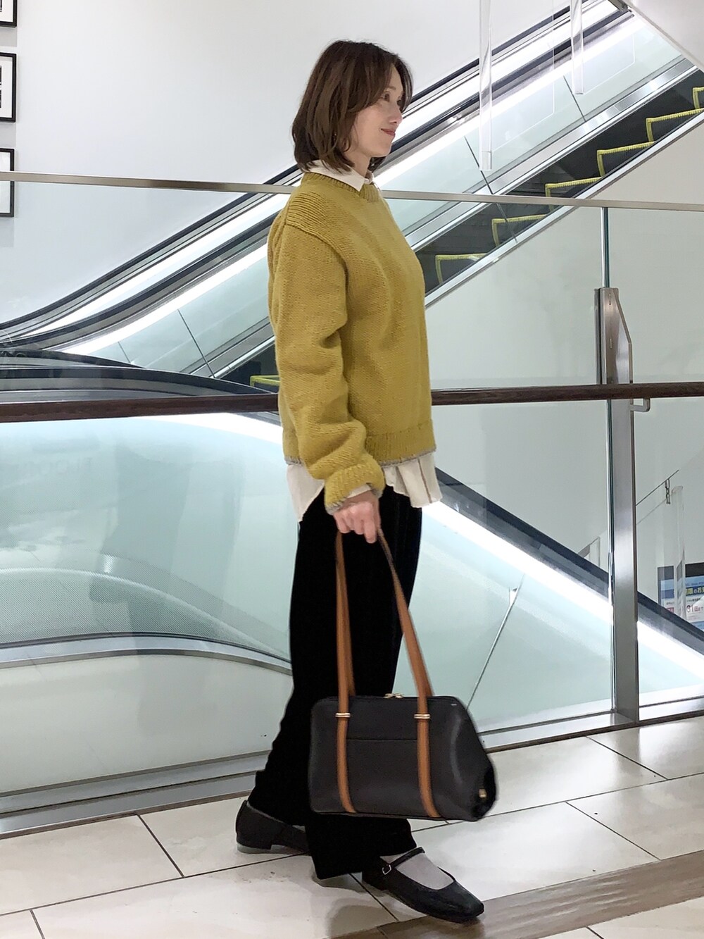 イエロー系のニット/セーター、ベージュ系のシャツ/ブラウス、ブラック系のその他パンツを着用したレディースの冬コーディネートの3枚目の写真