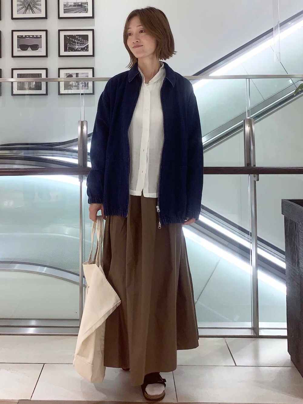 ホワイト系のトートバッグ、ブルー系のデニムジャケット、ホワイト系のシャツ/ブラウスを着用したレディースの夏コーディネートの2枚目の写真