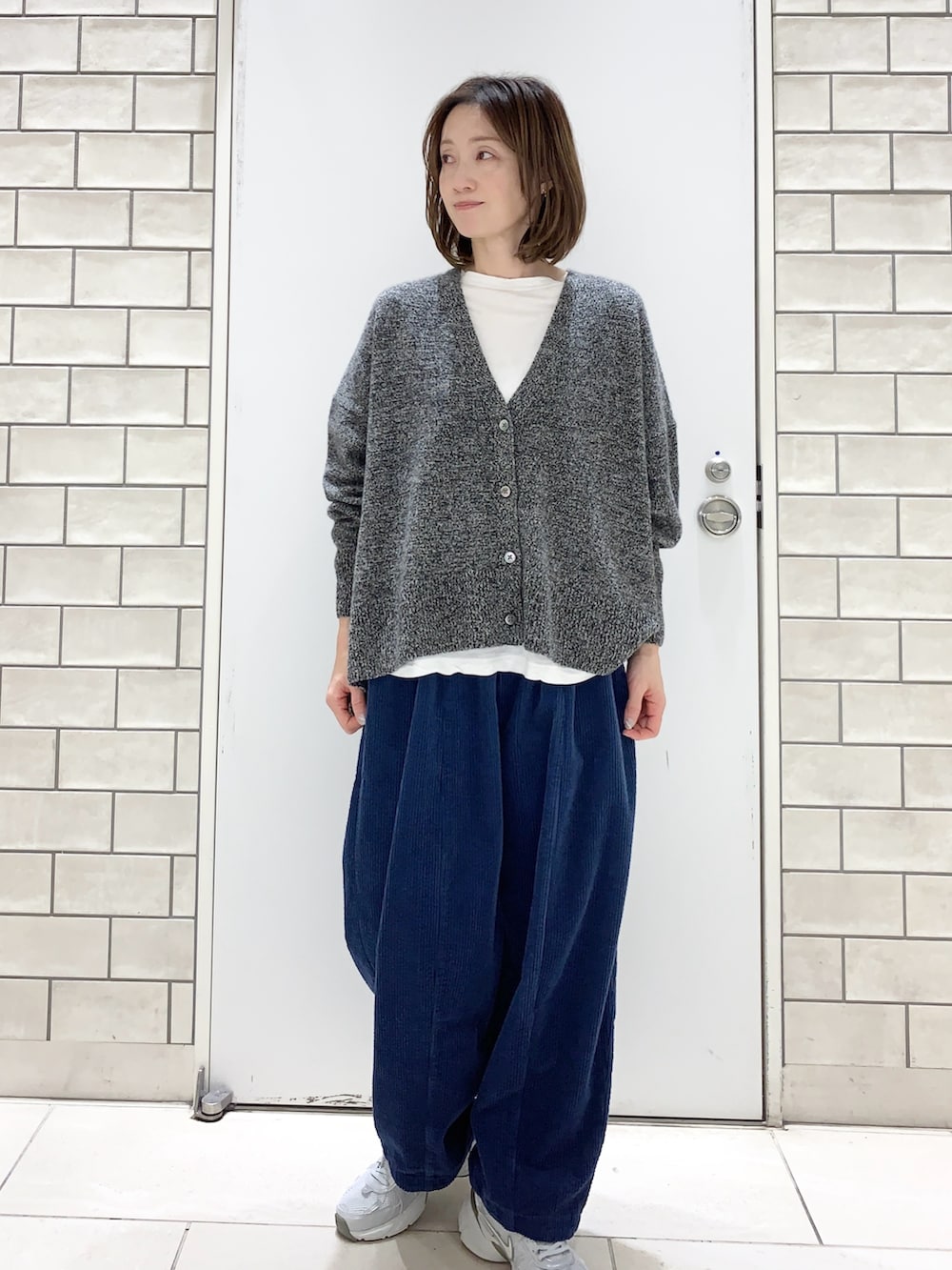 ブラック系のその他アウター、グレー系のニット/セーター、ホワイト系のスニーカーを着用したレディースの冬コーディネートの3枚目の写真