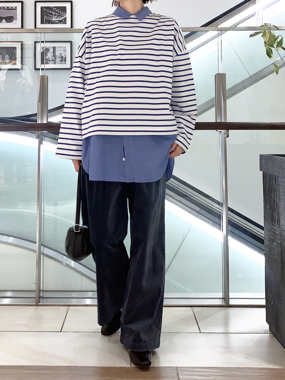 ブラック系のステンカラーコート、ブルー系のTシャツ/カットソー、ブルー系のその他パンツを着用したレディースの冬コーディネートの2枚目の写真