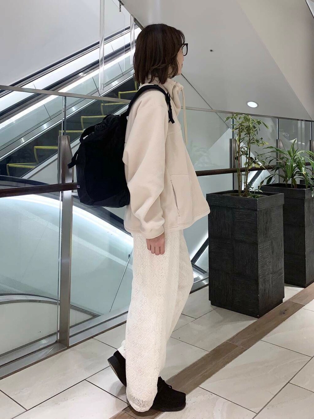 ブラウン系のステンカラーコート、ホワイト系のその他パンツ、ホワイト系のその他トップスを着用したレディースの冬コーディネートの4枚目の写真