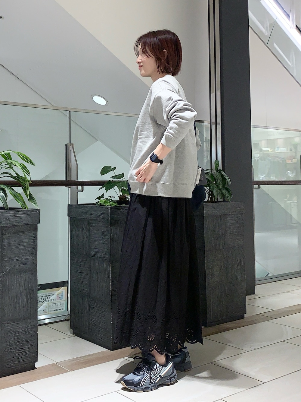 グレー系のスウェット、ブラック系のスカート、ブラック系のスニーカーを着用したレディースの冬コーディネートの2枚目の写真