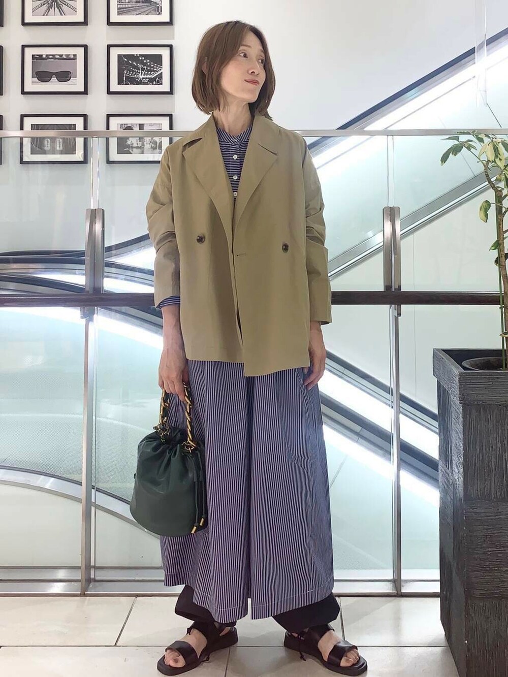 ブラック系のサンダル、グリーン系のショルダーバッグ、ブルー系のワンピースを着用したレディースの夏コーディネートの5枚目の写真