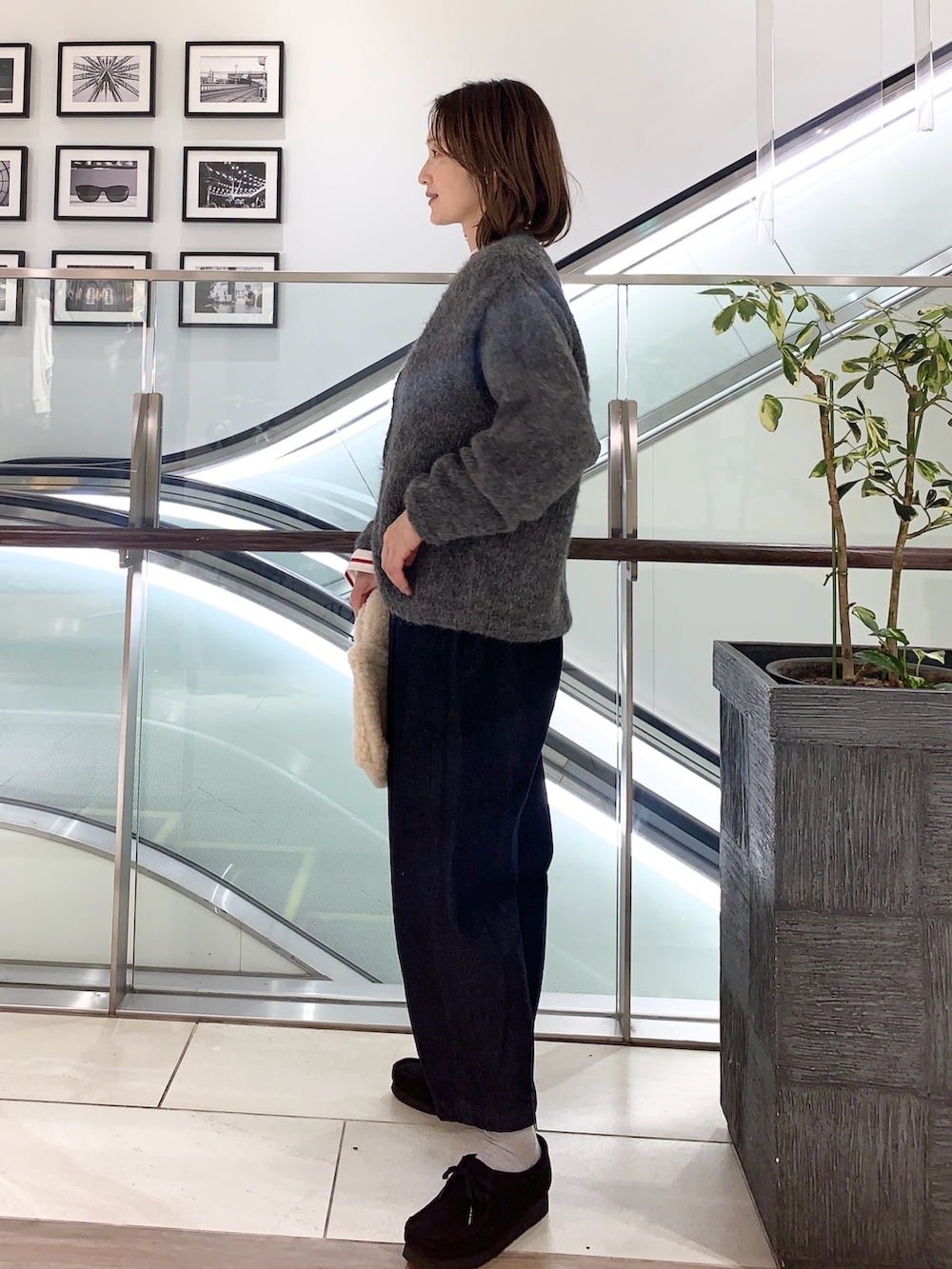 グレー系のカーディガン/ボレロ、レッド系のTシャツ/カットソー、ブルー系のデニムパンツを着用したレディースの冬コーディネートの2枚目の写真