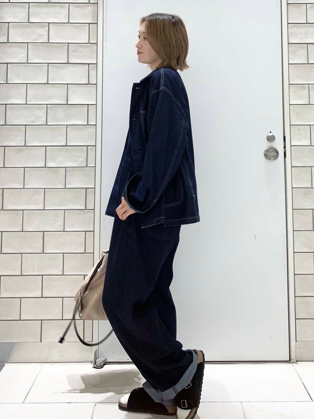 ベージュ系のトートバッグ、イエロー系のタンクトップ、ブルー系のデニムジャケットを着用したレディースの夏コーディネートの2枚目の写真