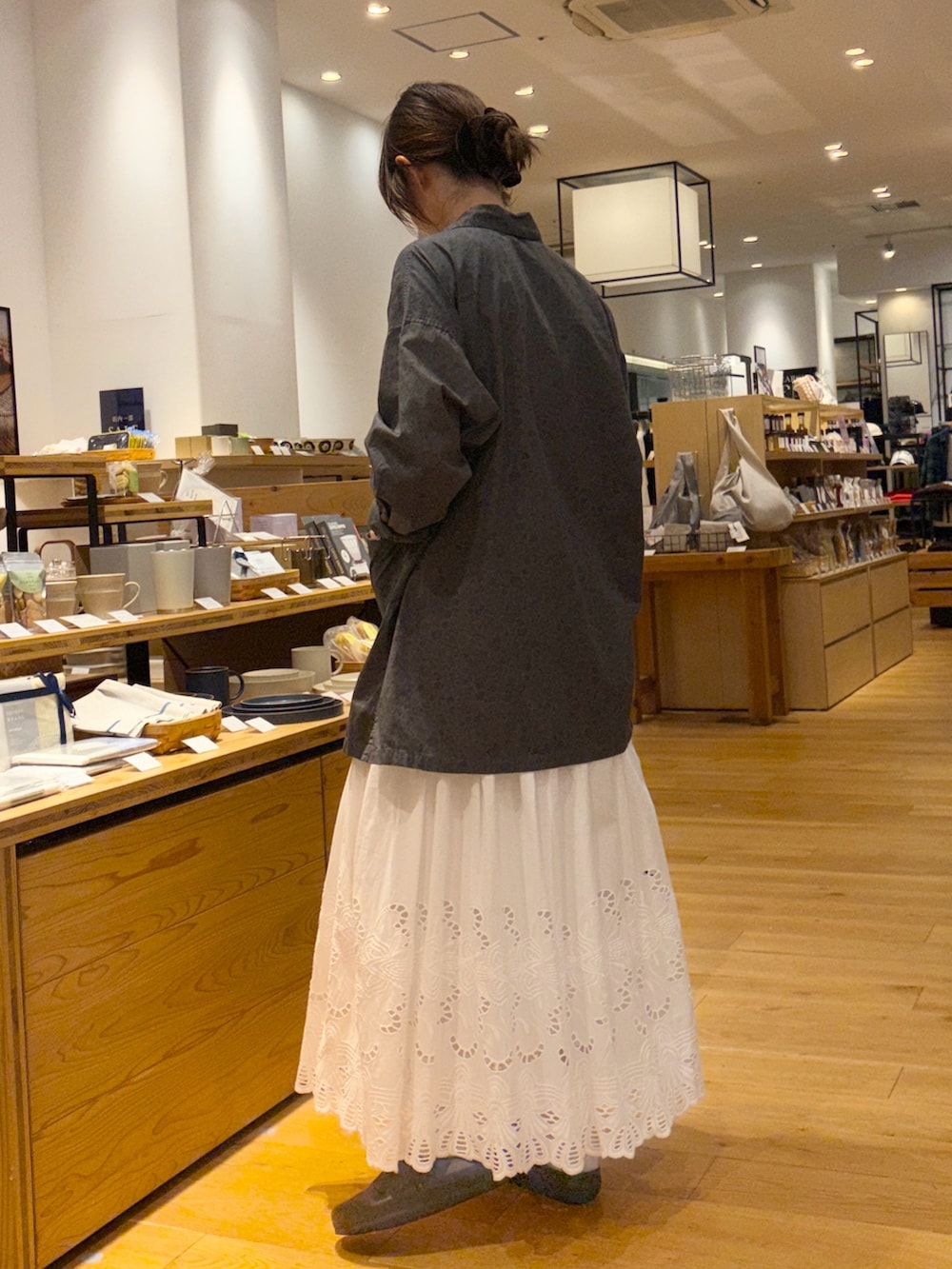 グレー系のシャツ/ブラウス、ホワイト系のスカート、ブラウン系のトートバッグを着用したレディースの秋コーディネートの2枚目の写真