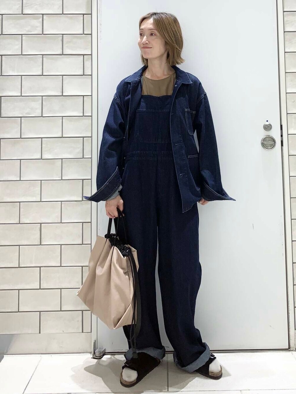 ベージュ系のトートバッグ、イエロー系のタンクトップ、ブルー系のデニムジャケットを着用したレディースの夏コーディネートの6枚目の写真