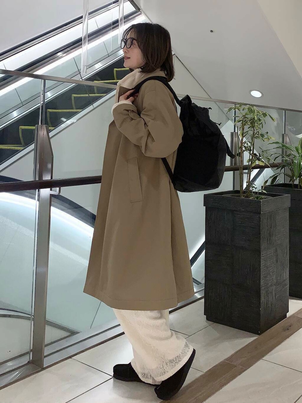 ブラウン系のステンカラーコート、ホワイト系のその他パンツ、ホワイト系のその他トップスを着用したレディースの冬コーディネートの3枚目の写真