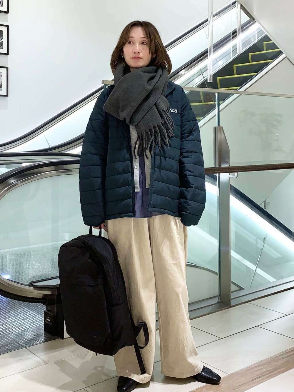 ブラック系のバックパック/リュック、ブルー系のダウンジャケット/コート、ブルー系のシャツ/ブラウスを着用したレディースの冬コーディネートの2枚目の写真