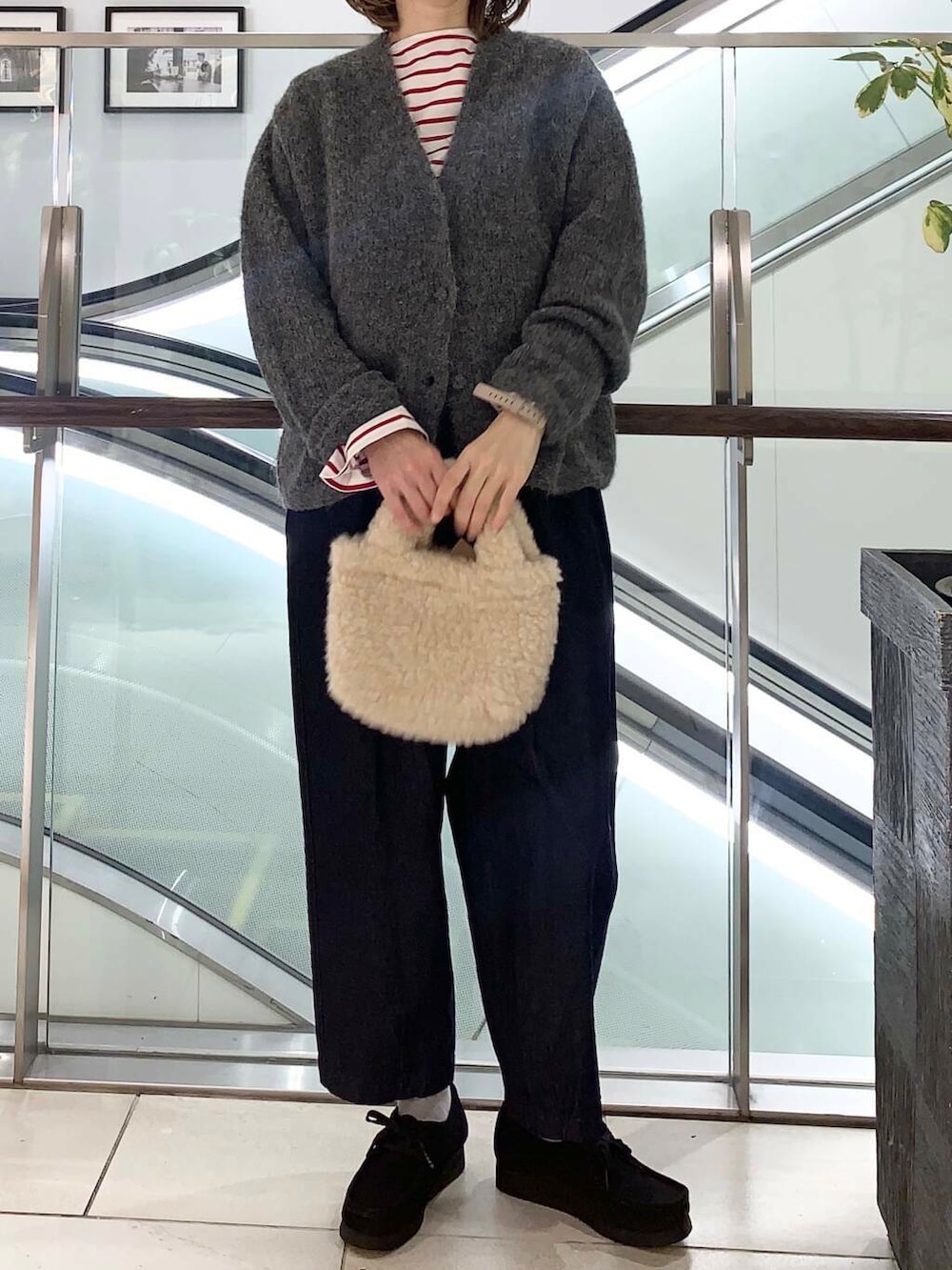 グレー系のカーディガン/ボレロ、レッド系のTシャツ/カットソー、ブルー系のデニムパンツを着用したレディースの冬コーディネートの4枚目の写真