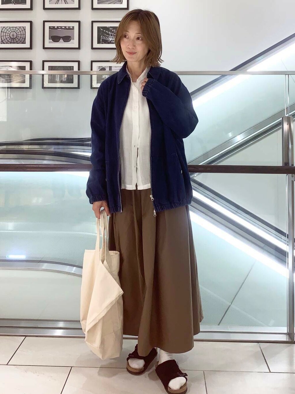 ホワイト系のトートバッグ、ブルー系のデニムジャケット、ホワイト系のシャツ/ブラウスを着用したレディースの夏コーディネートの7枚目の写真