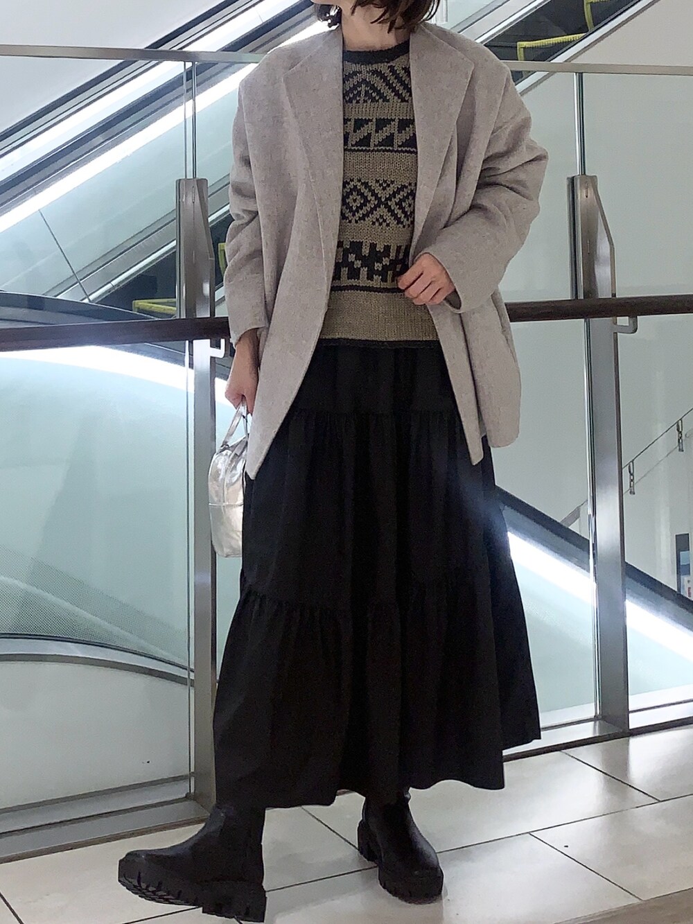 ブラック系のスカート、ベージュ系のニット/セーター、ベージュ系のその他アウターを着用したレディースの冬コーディネートの2枚目の写真