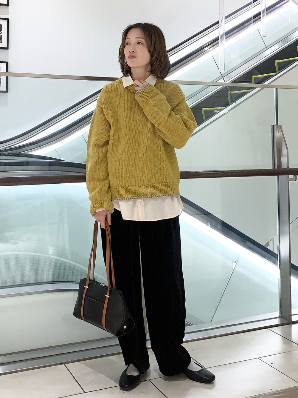 イエロー系のニット/セーター、ベージュ系のシャツ/ブラウス、ブラック系のその他パンツを着用したレディースの冬コーディネートの5枚目の写真