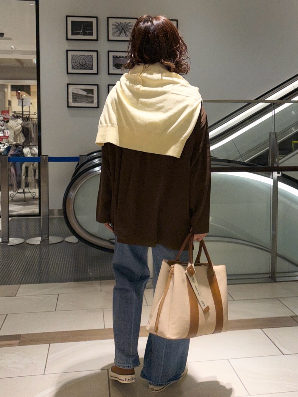 ブラウン系のシャツ/ブラウス、イエロー系のニット/セーター、ブルー系のデニムパンツを着用したレディースの冬コーディネートの3枚目の写真