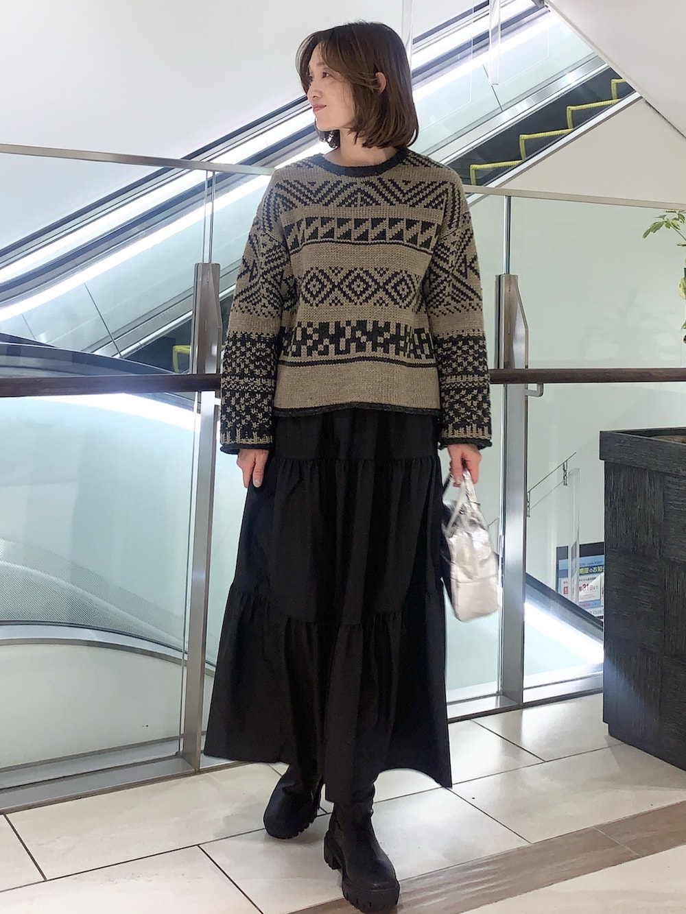 ブラック系のスカート、ベージュ系のニット/セーター、ベージュ系のその他アウターを着用したレディースの冬コーディネートの5枚目の写真