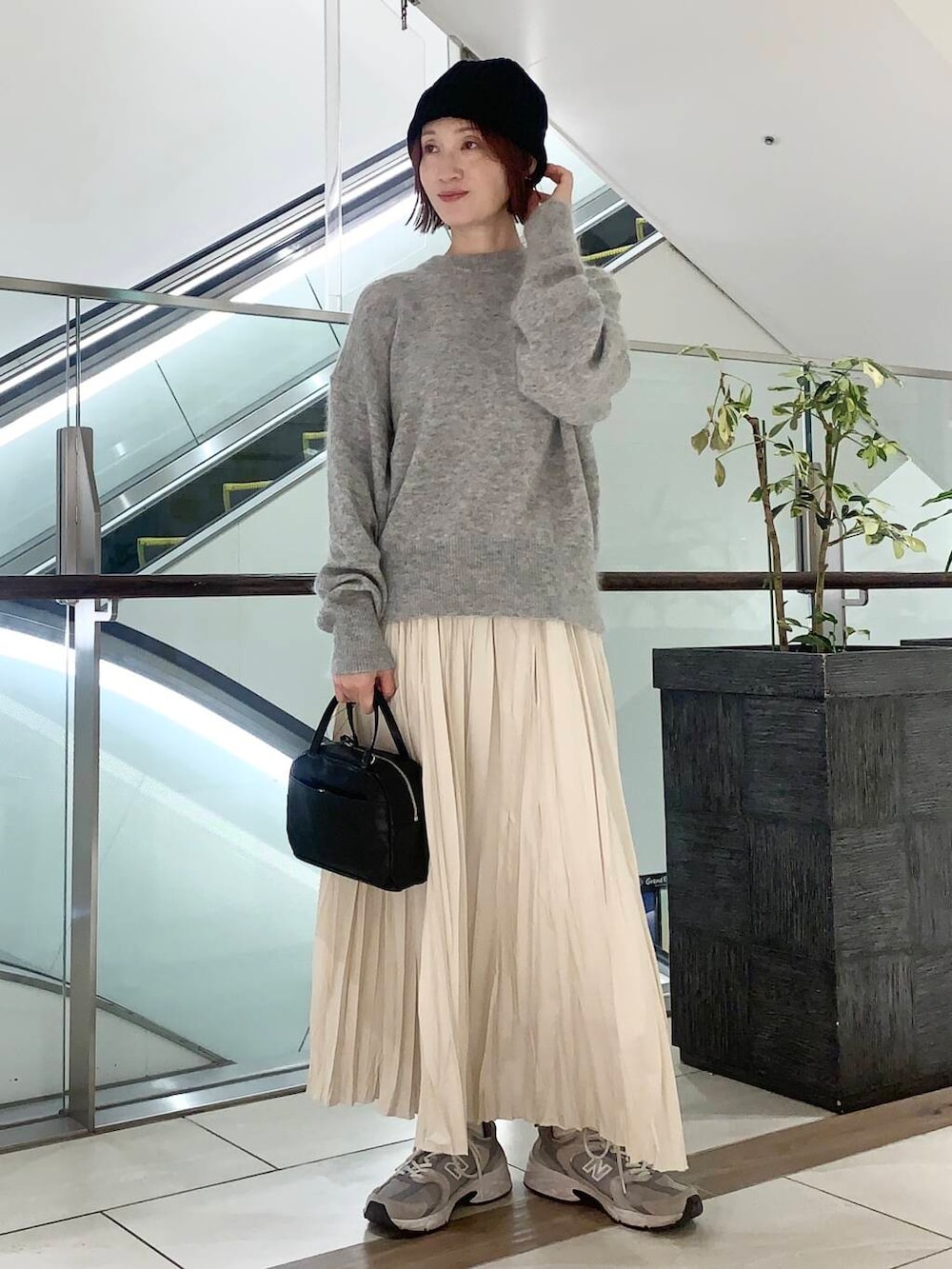 ブラック系のショルダーバッグ、ベージュ系のその他アウター、ホワイト系のスカートを着用したレディースの冬コーディネートの2枚目の写真