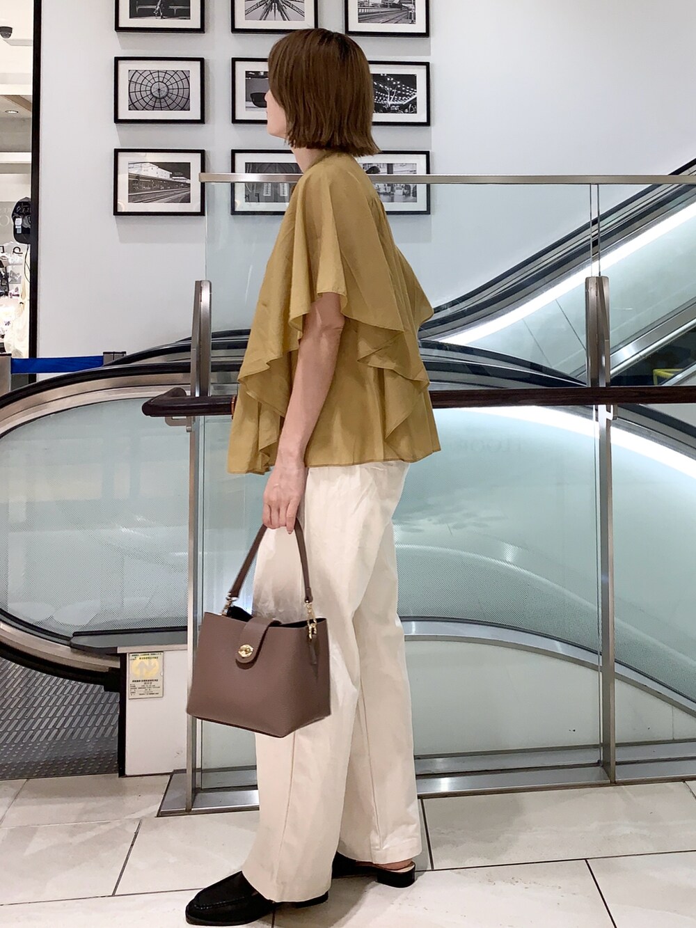 ホワイト系のパンツ、イエロー系のシャツ/ブラウス、ブラウン系のハンドバッグを着用したレディースの夏コーディネートの2枚目の写真