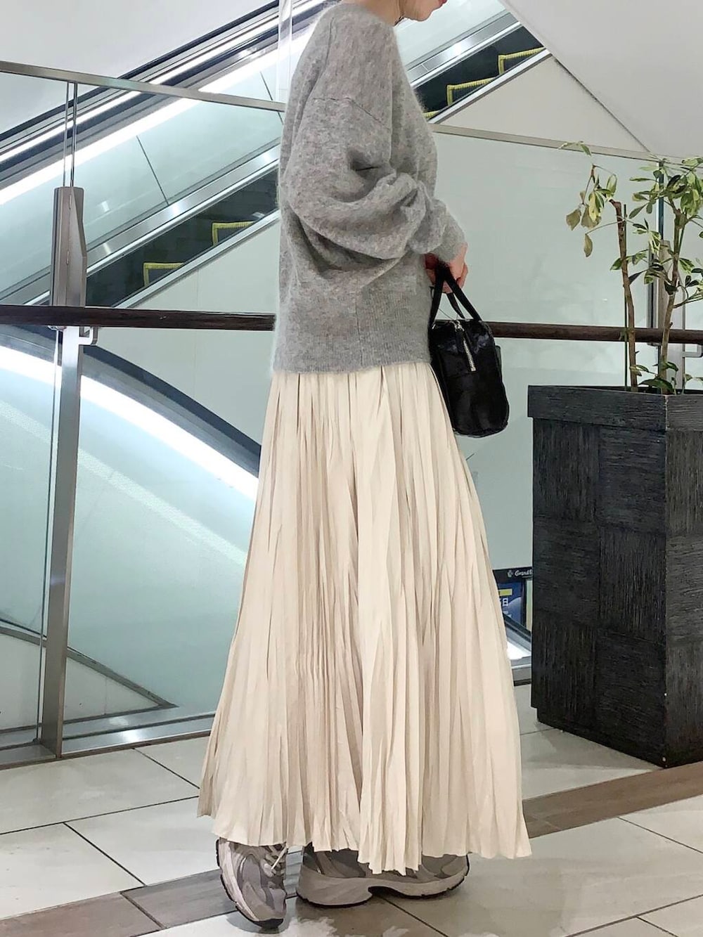 ブラック系のショルダーバッグ、ベージュ系のその他アウター、ホワイト系のスカートを着用したレディースの冬コーディネートの5枚目の写真