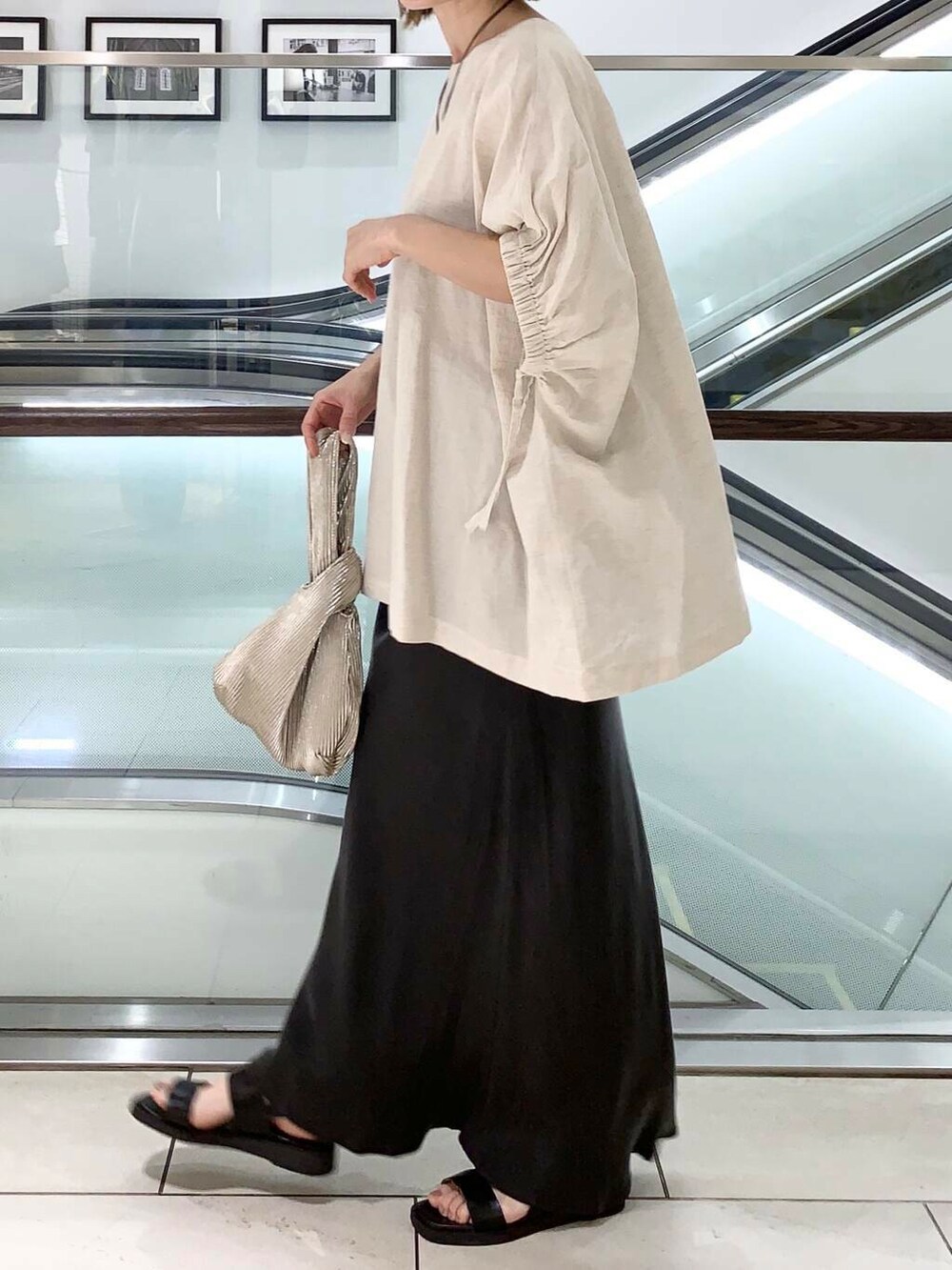 ブラック系のサンダル、ゴールド系のハンドバッグ、グレー系のスカートを着用したレディースの夏コーディネートの2枚目の写真