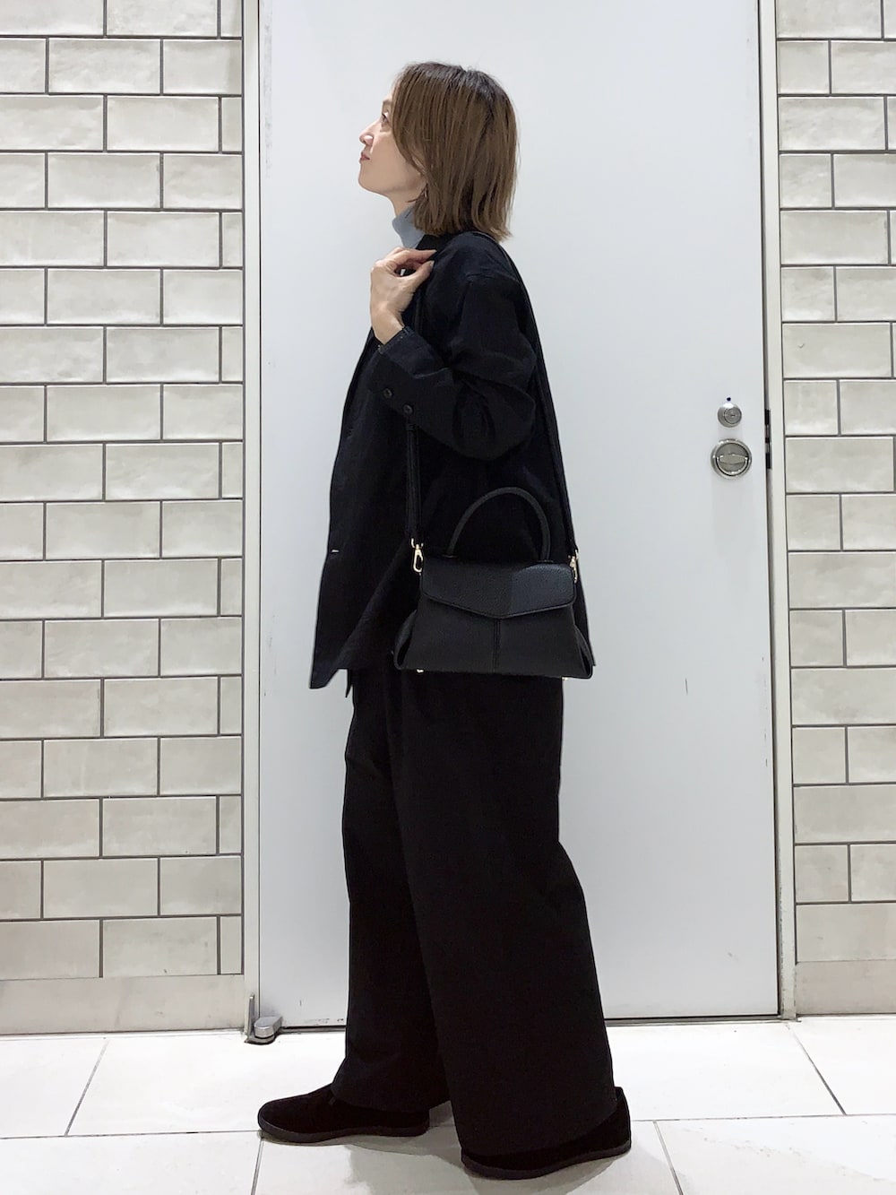 ブラック系のパンツ、ブラック系のテーラードジャケット、ブルー系のニット/セーターを着用したレディースの秋コーディネートの3枚目の写真