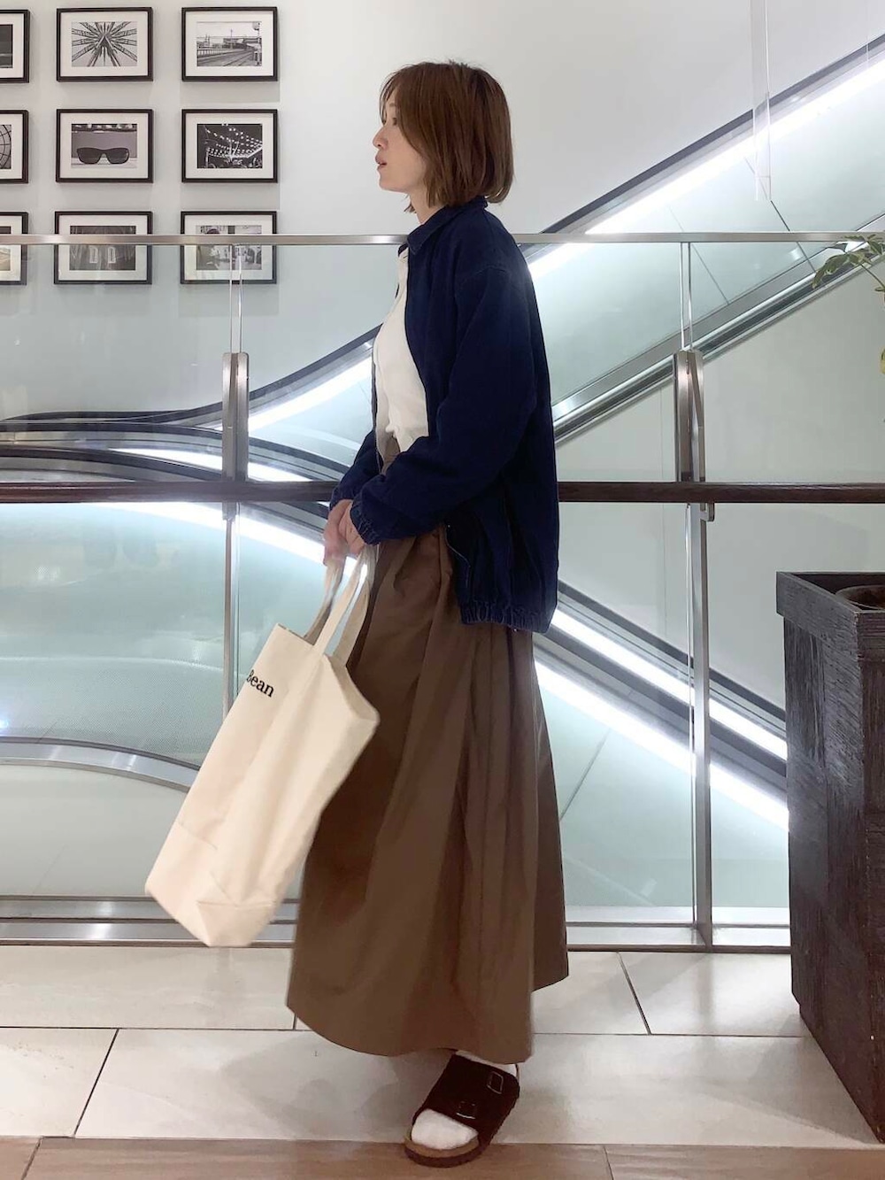 ホワイト系のトートバッグ、ブルー系のデニムジャケット、ホワイト系のシャツ/ブラウスを着用したレディースの夏コーディネートの3枚目の写真