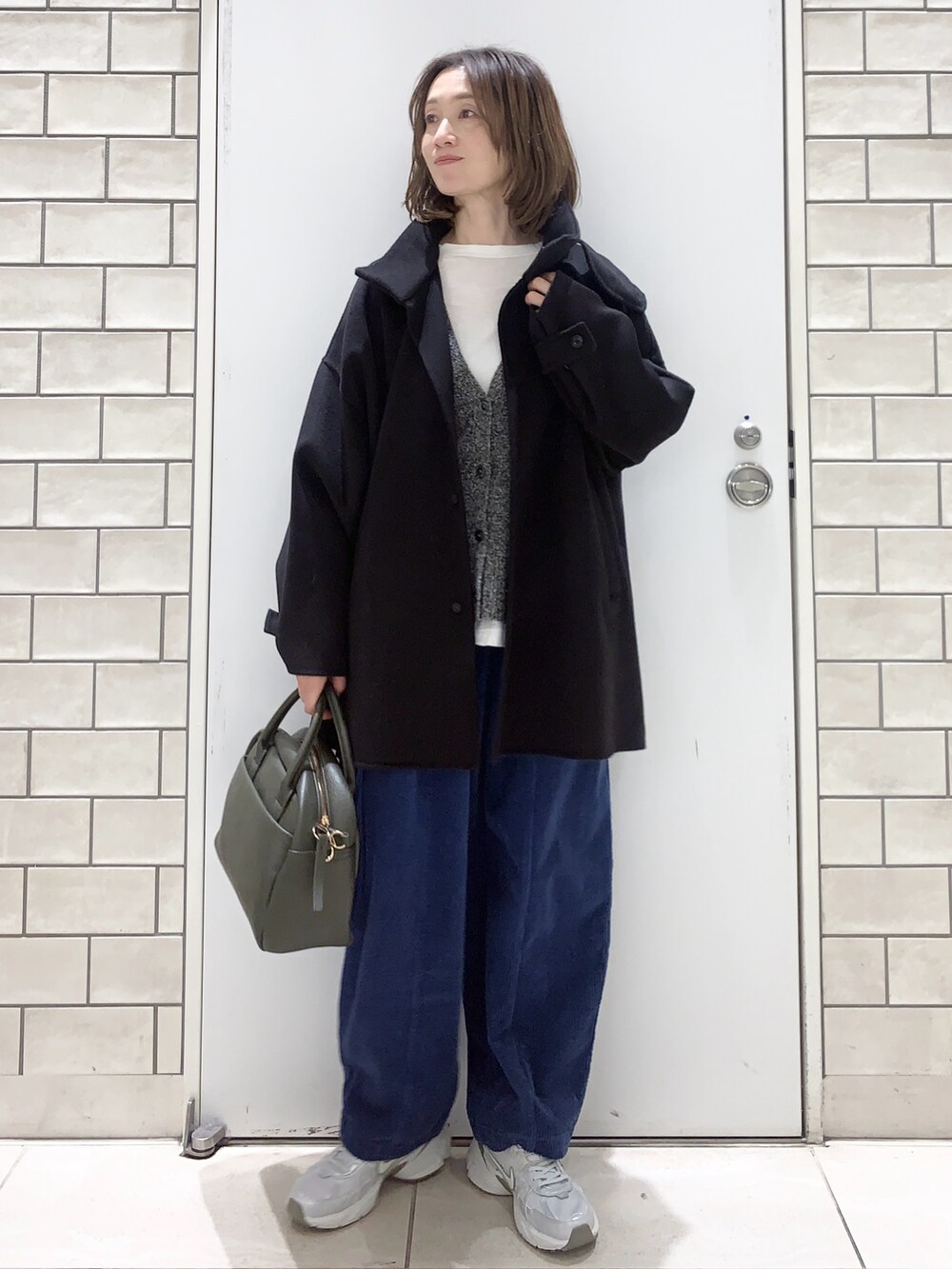 ブラック系のその他アウター、グレー系のニット/セーター、ホワイト系のスニーカーを着用したレディースの冬コーディネートの2枚目の写真