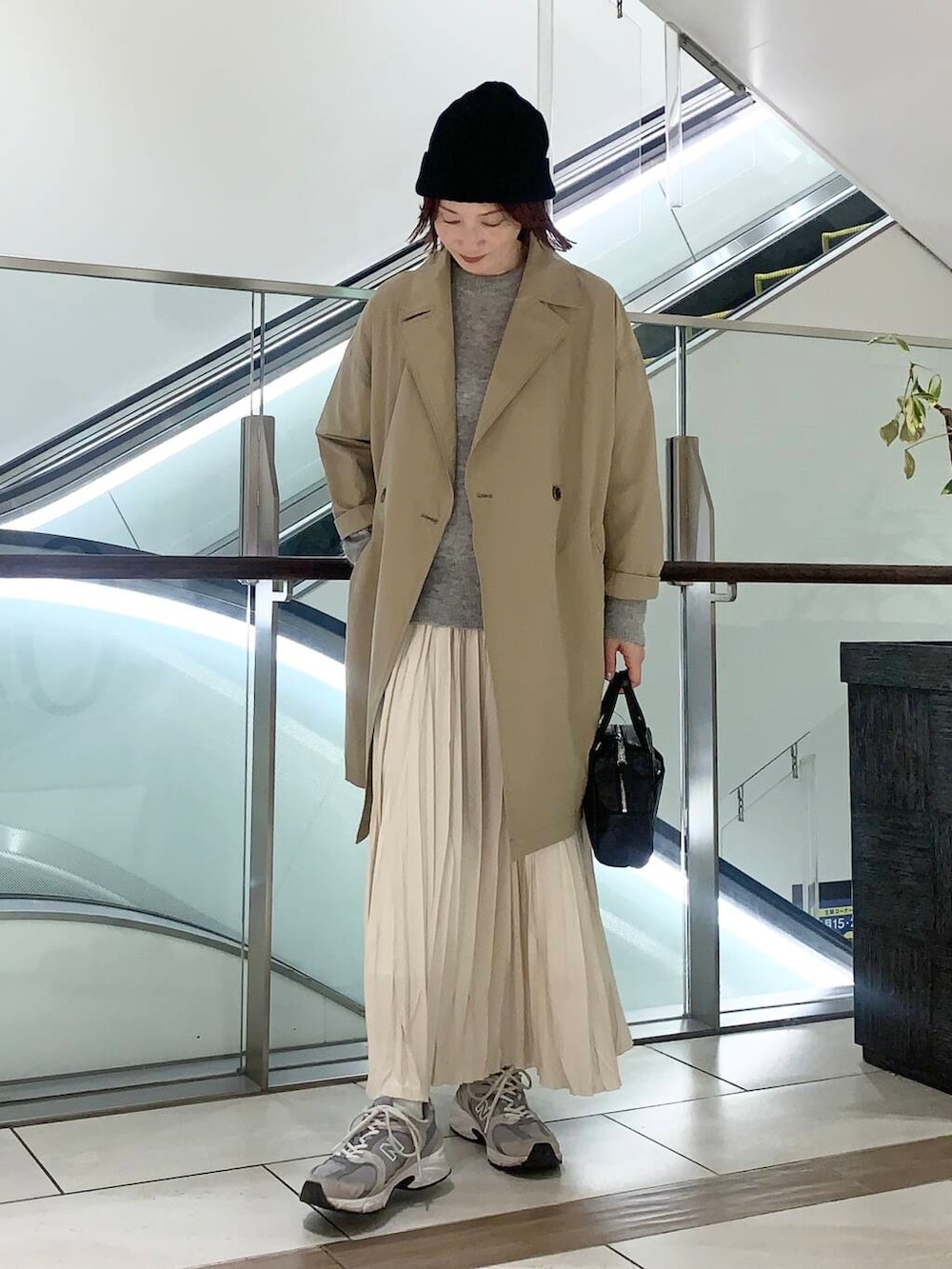 ブラック系のショルダーバッグ、ベージュ系のその他アウター、ホワイト系のスカートを着用したレディースの冬コーディネートの3枚目の写真