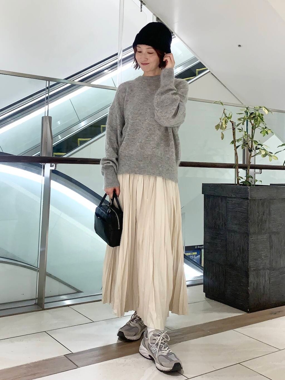 ブラック系のショルダーバッグ、ベージュ系のその他アウター、ホワイト系のスカートを着用したレディースの冬コーディネートの6枚目の写真