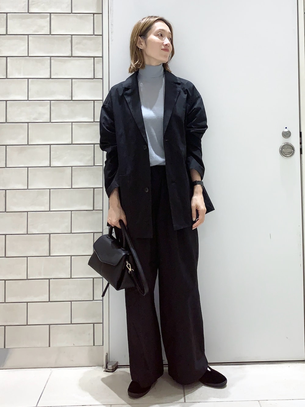 ブラック系のパンツ、ブラック系のテーラードジャケット、ブルー系のニット/セーターを着用したレディースの秋コーディネートの2枚目の写真