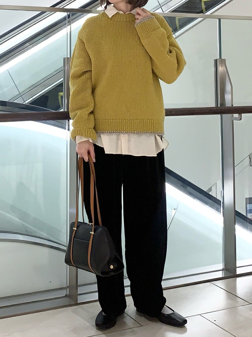 イエロー系のニット/セーター、ベージュ系のシャツ/ブラウス、ブラック系のその他パンツを着用したレディースの冬コーディネートの2枚目の写真