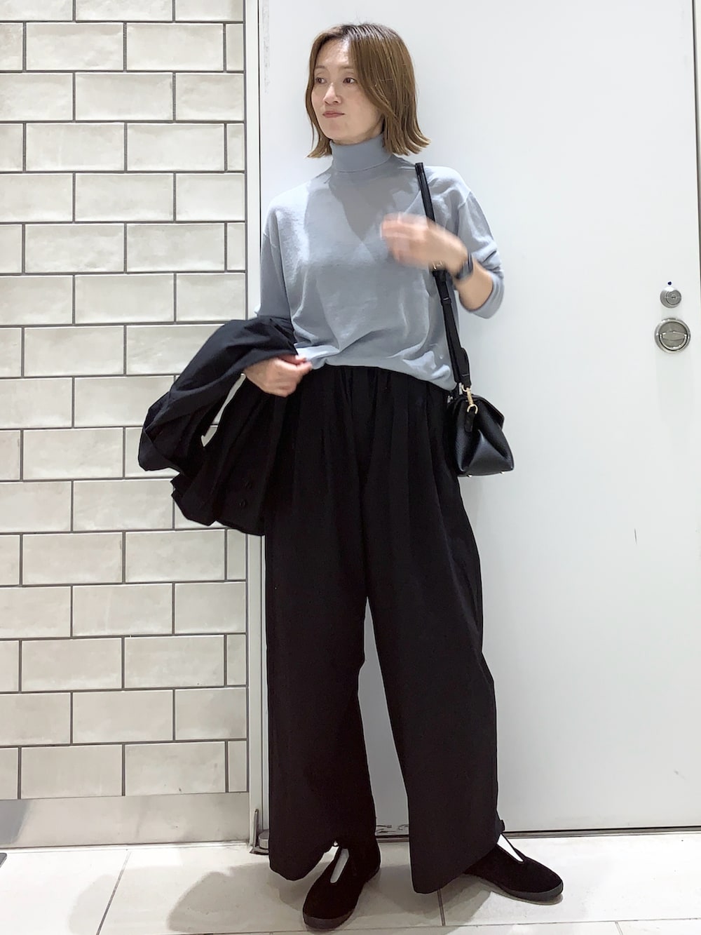 ブラック系のパンツ、ブラック系のテーラードジャケット、ブルー系のニット/セーターを着用したレディースの秋コーディネートの4枚目の写真
