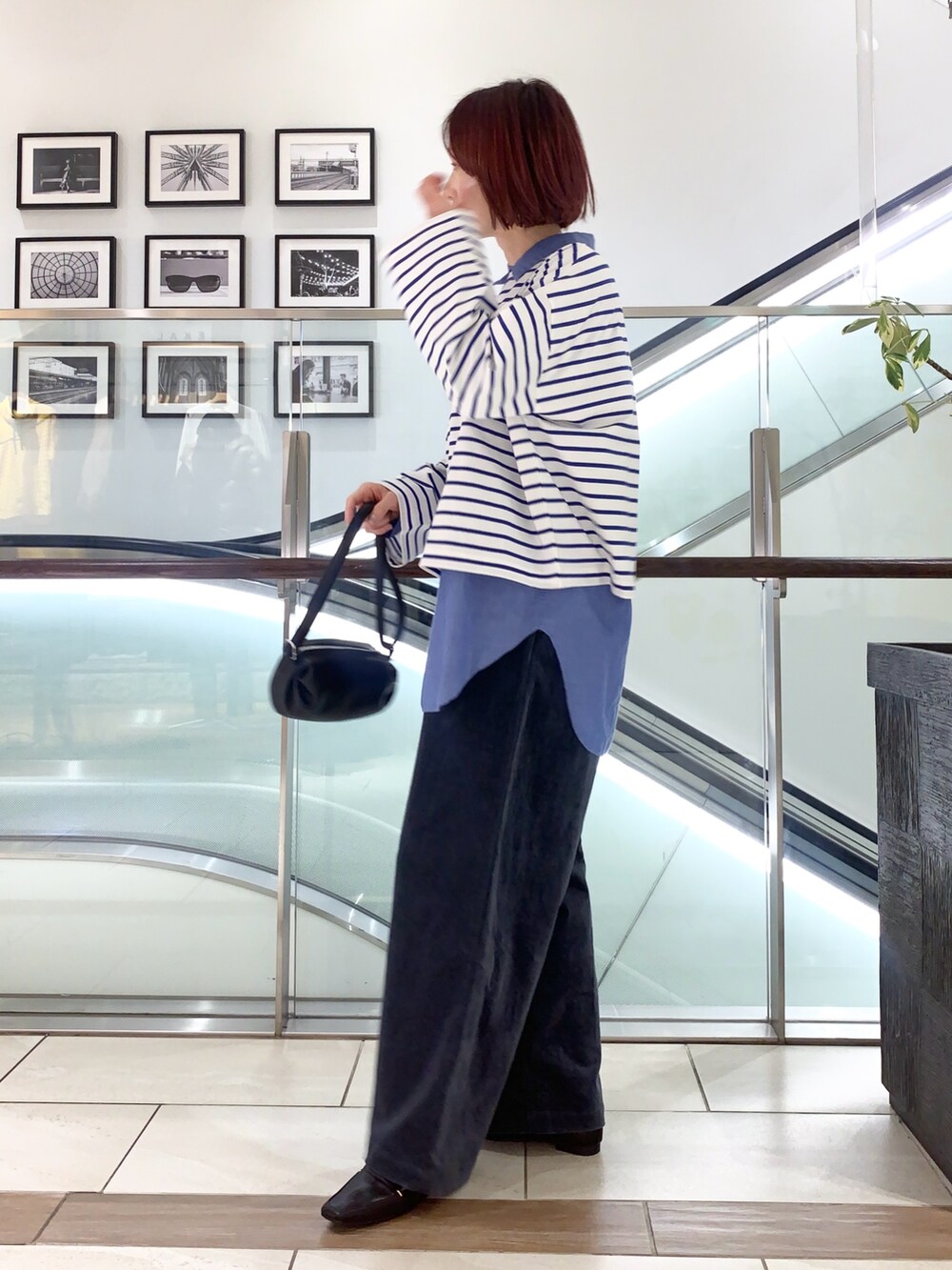 ブラック系のステンカラーコート、ブルー系のTシャツ/カットソー、ブルー系のその他パンツを着用したレディースの冬コーディネートの3枚目の写真