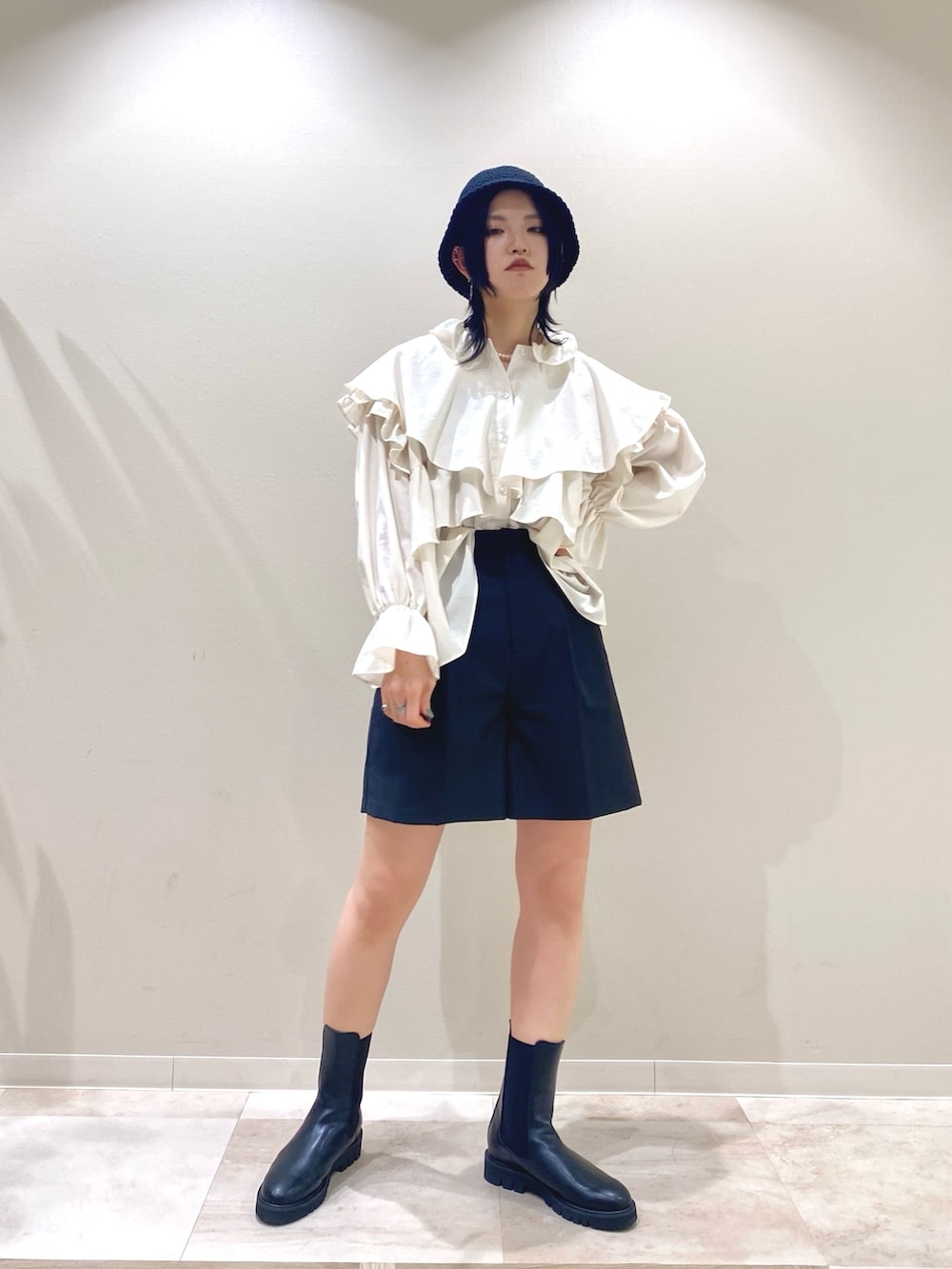 ブルー系のポンチョ、ホワイト系のシャツ/ブラウス、ブラック系のその他パンツを着用したレディースの春コーディネートの2枚目の写真