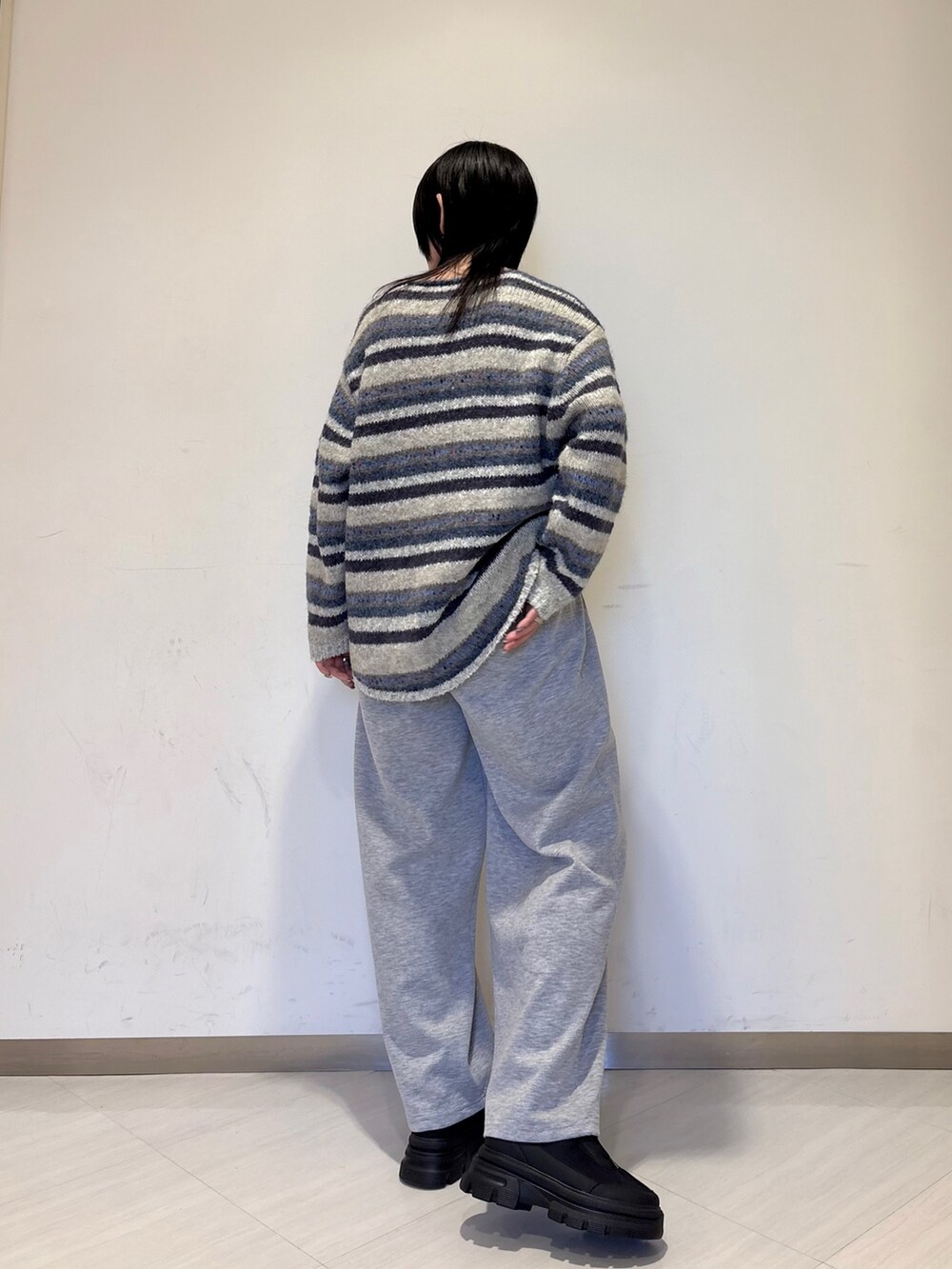 ブルー系のニット/セーター、グレー系のその他パンツ、ブラック系のスニーカーを着用したレディースの冬コーディネートの2枚目の写真