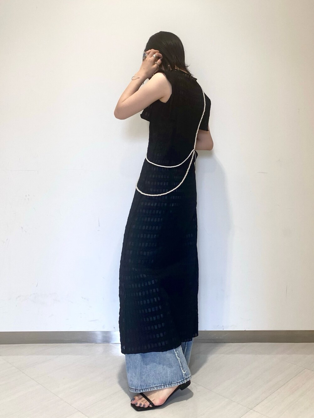 ブラック系のワンピース、ブルー系のデニムパンツ、ブラック系のサンダルを着用したレディースの春コーディネートの2枚目の写真