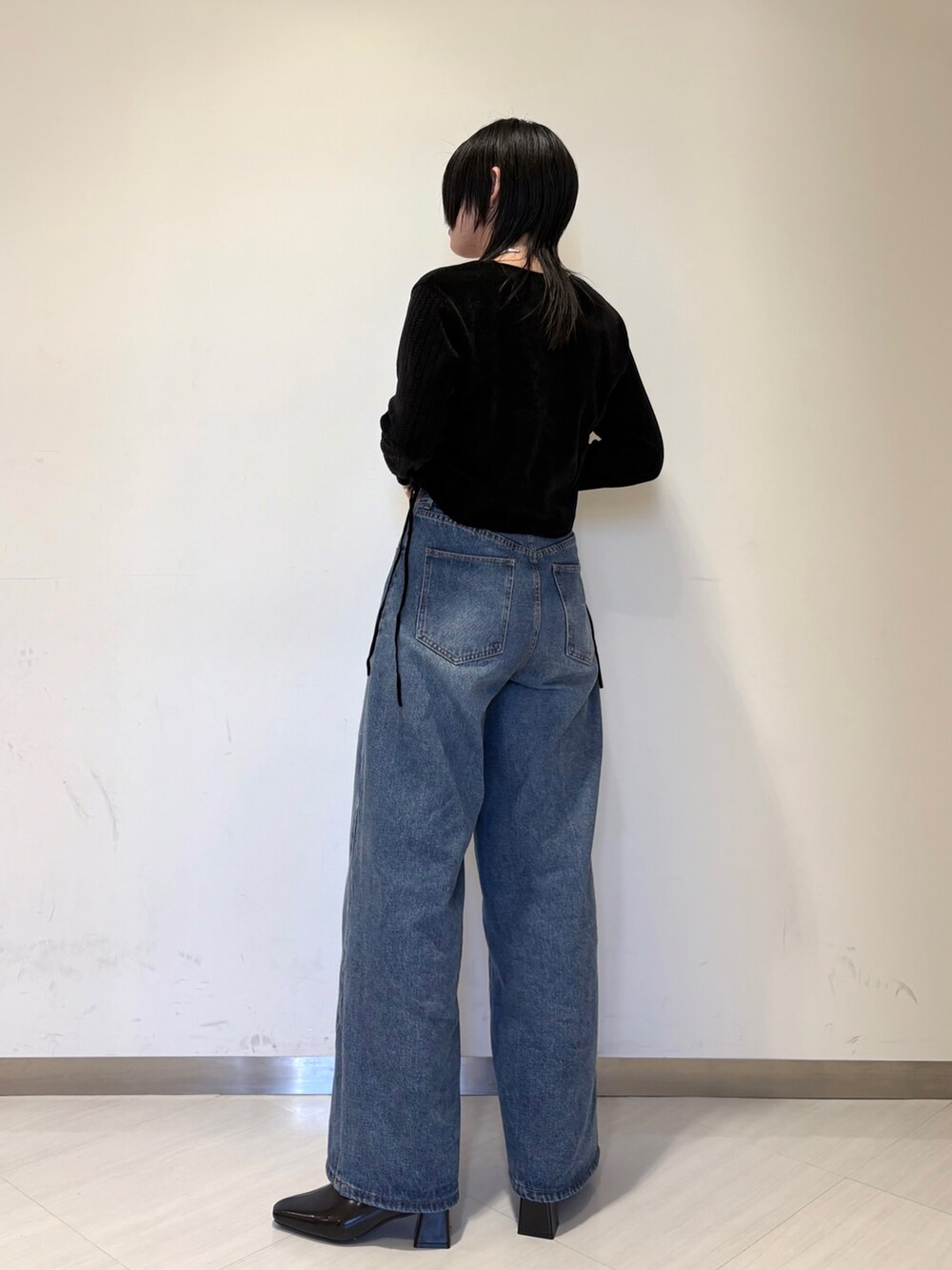 ブラック系のカーディガン/ボレロ、ブラック系のショルダーバッグ、ブルー系のデニムパンツを着用したレディースの冬コーディネートの2枚目の写真